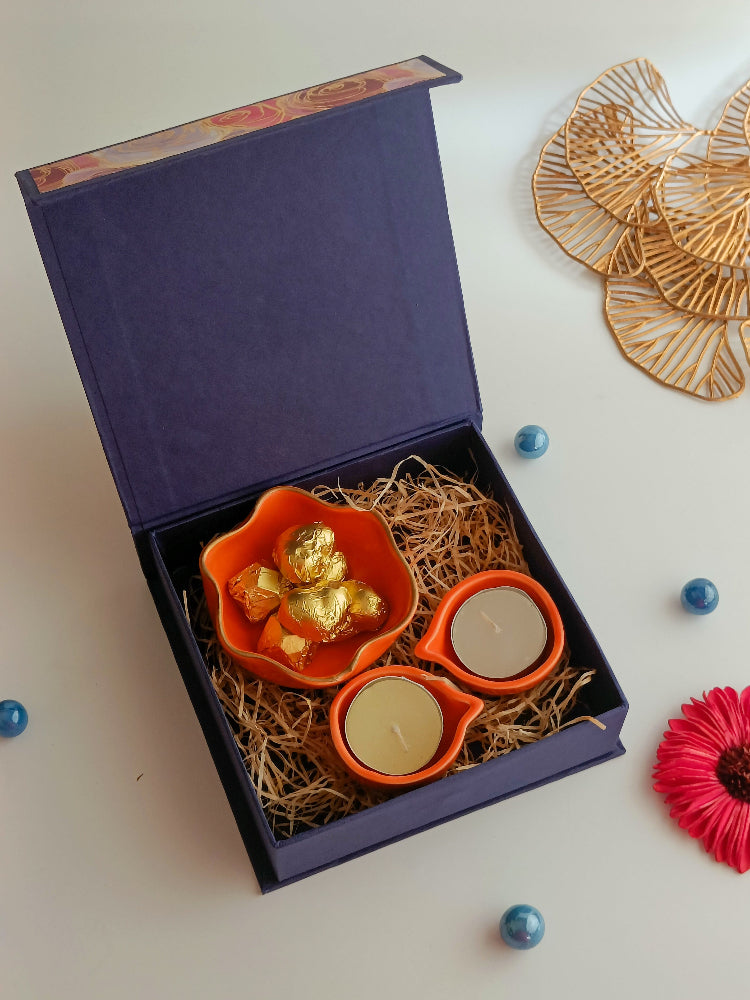 A gift box with ceramic diyas, tealight candle, handmade sweets in a ceramic bowl, a perfect box for ganesh chaturthi, housewarming, diwali and many more occassions.