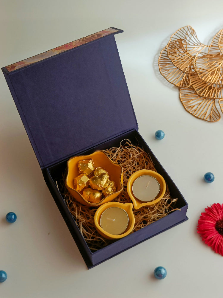 A gift box with ceramic diyas, tealight candle, handmade sweets in a ceramic bowl, a perfect box for ganesh chaturthi, housewarming, diwali and many more occassions.
